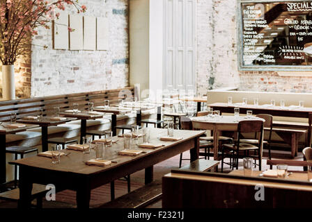 Ein Restaurant mit langen, schmalen Tische und Stühle für eine Mahlzeit gelegt. Eine große Tafel Menü. Stockfoto