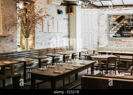 Ein Restaurant mit langen, schmalen Tische und Stühle für eine Mahlzeit gelegt. Eine große Tafel Menü. Stockfoto
