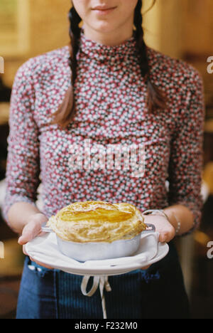 Eine Frau, die ein frisches gebackenes Gebäck gekrönt Kuchen auf einen Teller. Stockfoto