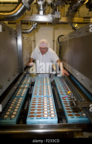 Ein Arbeiter inspiziert eiförmigen Formen auf der Fertigungslinie Cadbury Creme Eier in Bournville. Stockfoto