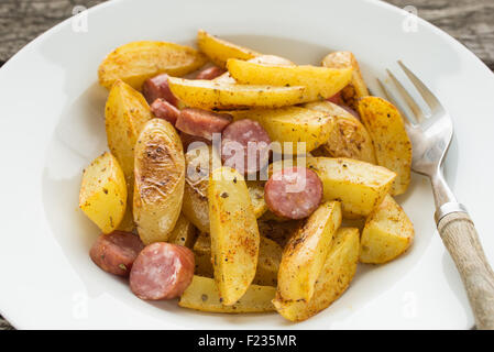 Gewürzte Bratkartoffeln mit Würstchen und Gabel hautnah Stockfoto