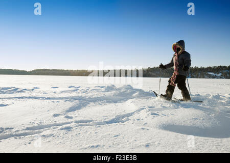 Erwachsene Frau Schneeschuhen über eine verschneite zugefrorenen See in Ely, Minnesota auf einer kalten Minustemperaturen Temperatur Wintertag Stockfoto