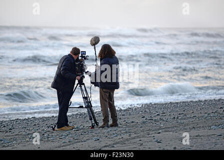 Kameramann und Ton Tonmeister bei der Arbeit an einem New Zealand Strand bei Sonnenuntergang Stockfoto