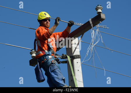 GREYMOUTH, Neuseeland, 5. August 2015: Ein Linienrichter Drähte oben ein Netz Stromversorgungskabel auf einen neuen Pfosten Stockfoto