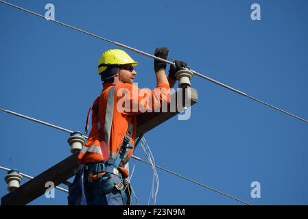 Ein Linienrichter Drähte oben ein Netz Stromversorgungskabel auf einen neuen Pfosten Stockfoto