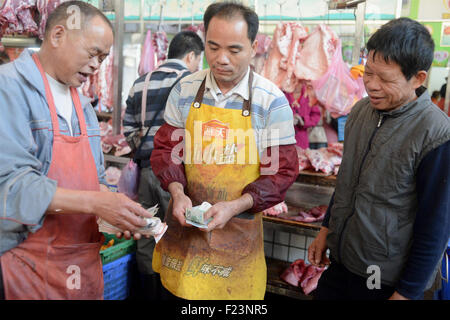 Dongguan, Guangdong, CHN. 1. Januar 2015. Dongguan, CHINA - 1. Januar 2015: (Nur zur redaktionellen Verwendung. CHINA aus) Mastschwein Händler Liu steht auf und geht auf den Markt mit Messern und einer Fackel bei 0:30 Uhr jeden Tag, zusammen mit seiner Assistentin und Schwiegertochter Frau Huang. Dutzende von Schweinen sind verpackt in seinem Stall, später schneidet er vier Beine, Frau Huang entfernt Haare an Beinen Schwein. Wenn Fleisch vom Knochen vollständig geschält ist, wird er eine rauchen, dann das Fleisch in Stücke schneiden. Jedes Stück ist mindestens 10 kg weil Liu ist ein Großhändler. Und seine Acquaintancs kommen, fast dieselben Menge zu holen. Und er endet bu Stockfoto