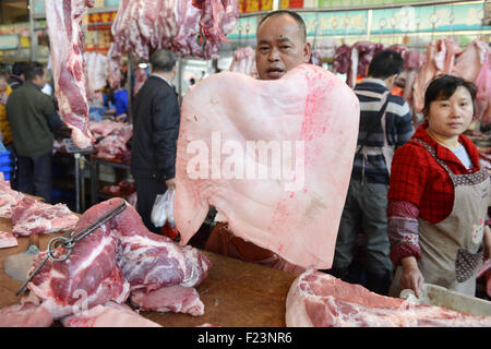 Dongguan, Guangdong, CHN. 1. Januar 2015. Dongguan, CHINA - 1. Januar 2015: (Nur zur redaktionellen Verwendung. CHINA aus) Mastschwein Händler Liu steht auf und geht auf den Markt mit Messern und einer Fackel bei 0:30 Uhr jeden Tag, zusammen mit seiner Assistentin und Schwiegertochter Frau Huang. Dutzende von Schweinen sind verpackt in seinem Stall, später schneidet er vier Beine, Frau Huang entfernt Haare an Beinen Schwein. Wenn Fleisch vom Knochen vollständig geschält ist, wird er eine rauchen, dann das Fleisch in Stücke schneiden. Jedes Stück ist mindestens 10 kg weil Liu ist ein Großhändler. Und seine Acquaintancs kommen, fast dieselben Menge zu holen. Und er endet bu Stockfoto