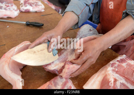 Dongguan, Guangdong, CHN. 1. Januar 2015. Dongguan, CHINA - 1. Januar 2015: (Nur zur redaktionellen Verwendung. CHINA aus) Mastschwein Händler Liu steht auf und geht auf den Markt mit Messern und einer Fackel bei 0:30 Uhr jeden Tag, zusammen mit seiner Assistentin und Schwiegertochter Frau Huang. Dutzende von Schweinen sind verpackt in seinem Stall, später schneidet er vier Beine, Frau Huang entfernt Haare an Beinen Schwein. Wenn Fleisch vom Knochen vollständig geschält ist, wird er eine rauchen, dann das Fleisch in Stücke schneiden. Jedes Stück ist mindestens 10 kg weil Liu ist ein Großhändler. Und seine Acquaintancs kommen, fast dieselben Menge zu holen. Und er endet bu Stockfoto