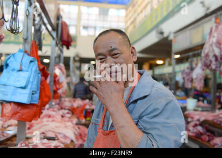 Dongguan, Guangdong, CHN. 1. Januar 2015. Dongguan, CHINA - 1. Januar 2015: (Nur zur redaktionellen Verwendung. CHINA aus) Mastschwein Händler Liu steht auf und geht auf den Markt mit Messern und einer Fackel bei 0:30 Uhr jeden Tag, zusammen mit seiner Assistentin und Schwiegertochter Frau Huang. Dutzende von Schweinen sind verpackt in seinem Stall, später schneidet er vier Beine, Frau Huang entfernt Haare an Beinen Schwein. Wenn Fleisch vom Knochen vollständig geschält ist, wird er eine rauchen, dann das Fleisch in Stücke schneiden. Jedes Stück ist mindestens 10 kg weil Liu ist ein Großhändler. Und seine Acquaintancs kommen, fast dieselben Menge zu holen. Und er endet bu Stockfoto