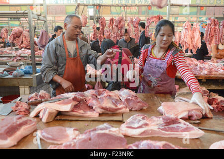 Dongguan, Guangdong, CHN. 1. Januar 2015. Dongguan, CHINA - 1. Januar 2015: (Nur zur redaktionellen Verwendung. CHINA aus) Mastschwein Händler Liu steht auf und geht auf den Markt mit Messern und einer Fackel bei 0:30 Uhr jeden Tag, zusammen mit seiner Assistentin und Schwiegertochter Frau Huang. Dutzende von Schweinen sind verpackt in seinem Stall, später schneidet er vier Beine, Frau Huang entfernt Haare an Beinen Schwein. Wenn Fleisch vom Knochen vollständig geschält ist, wird er eine rauchen, dann das Fleisch in Stücke schneiden. Jedes Stück ist mindestens 10 kg weil Liu ist ein Großhändler. Und seine Acquaintancs kommen, fast dieselben Menge zu holen. Und er endet bu Stockfoto