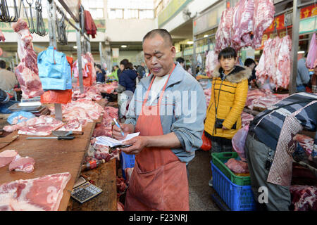 Dongguan, Guangdong, CHN. 1. Januar 2015. Dongguan, CHINA - 1. Januar 2015: (Nur zur redaktionellen Verwendung. CHINA aus) Mastschwein Händler Liu steht auf und geht auf den Markt mit Messern und einer Fackel bei 0:30 Uhr jeden Tag, zusammen mit seiner Assistentin und Schwiegertochter Frau Huang. Dutzende von Schweinen sind verpackt in seinem Stall, später schneidet er vier Beine, Frau Huang entfernt Haare an Beinen Schwein. Wenn Fleisch vom Knochen vollständig geschält ist, wird er eine rauchen, dann das Fleisch in Stücke schneiden. Jedes Stück ist mindestens 10 kg weil Liu ist ein Großhändler. Und seine Acquaintancs kommen, fast dieselben Menge zu holen. Und er endet bu Stockfoto