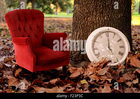 Entspannen ist Herbst Zeit Konzept Vintage-Hintergrund. Erzählen Sie eine Herbst Geschichte kreative Idee Fotografie mit Baum, Uhr und roten Sofa. Stockfoto