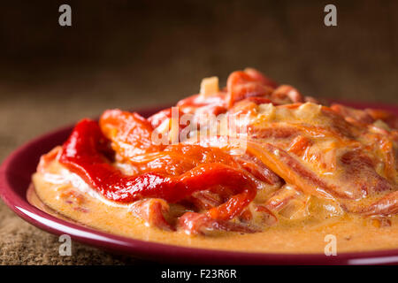 Essen gebratene Paprika mit Sahne auf einem roten Teller Stockfoto