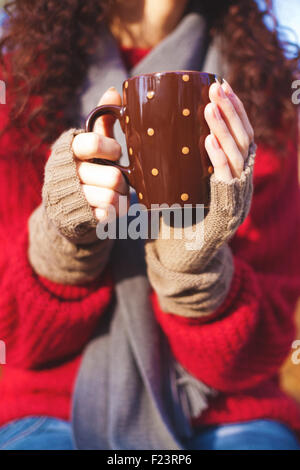 Mädchen in wollene Handschuhe, Pullover und Schal hält eine Tasse trinken Stockfoto