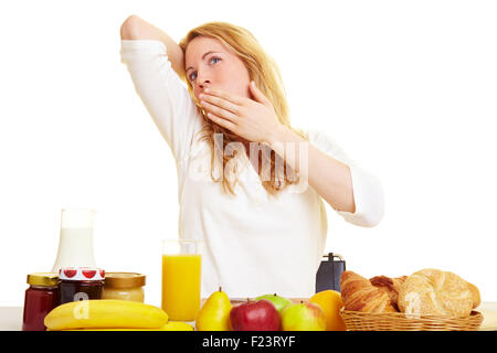 Frau am Morgen auf dem Frühstückstisch Gähnen Stockfoto