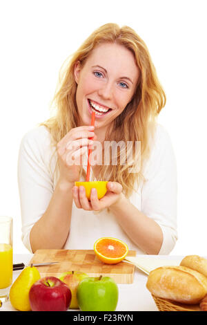 Blonde glückliche Frau trinken den Saft von einer orange Stockfoto