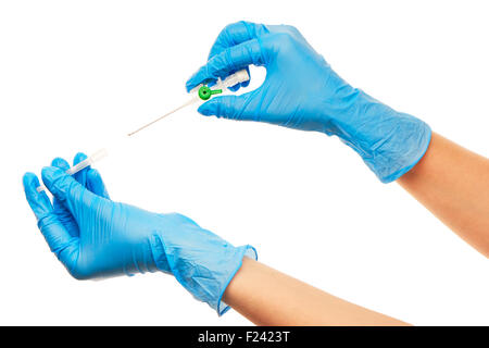 Nahaufnahme eines weiblichen Arzt Hände in blau sterilisierte OP-Handschuhe mit grünen Kunststoff Katheter vor weißem Hintergrund Stockfoto