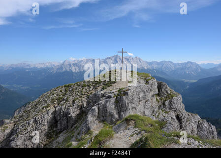 Gipfelkreuz des Berges Schellschlicht und das Zugspitz-massiv im Hintergrund, Grainau, Deutschland Stockfoto