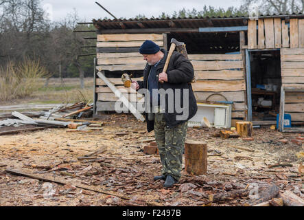 Ganzkörper-Porträt des alten ukrainischen Bauern mit einer Axt Stockfoto