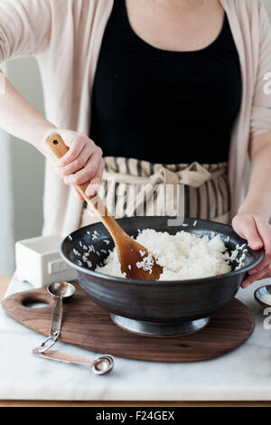 Die Herstellung von Sushi. Frau Reis in einer Schüssel mischen. Stockfoto