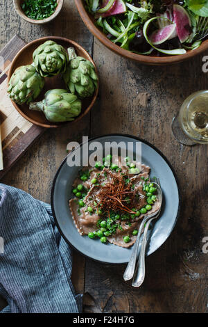 Kastanienmehl Ravioli mit Artischocken, Erbsen, Brühe und Enoki Pilze Strohhalme. Stockfoto