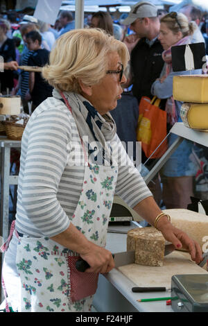 Französische Stall Inhaber in Sarlat am Markttag schneiden und Verkauf von Käse Stockfoto