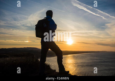 Saltburn-by-the-Sea, Yorkshire, Großbritannien. 11. September, 2015. Wetter: Walker auf The Cleveland Way coastal Footpath bei Sonnenuntergang auf Felsen (gehören zu den höchsten in England an diesem Küstenabschnitt der Yorkshire) über Saltburn aufsaugen der späten Nachmittagssonne am Ende einen herrlichen Tag an der Küste von North Yorkshire. Regen wird voraussichtlich am Freitag und Samstag in weiten Teilen des Vereinigten Königreichs vom Atlantik fegen. Kleinen Sundog oder Parhelion Regenbogen auf der linken Seite von Walker. Diese entstehen durch Sonnenlicht durch Eiskristalle auf hohem Niveau. Bildnachweis: Alan Dawson News/Alamy Live-Nachrichten Stockfoto