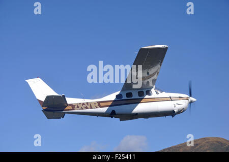 Ein unter Druck stehendes Cessna 210 fliegt über der malerischen Westküste von Neuseeland Stockfoto