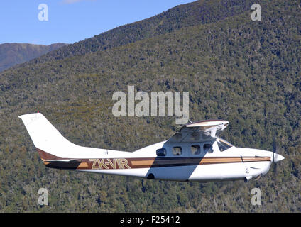 Ein unter Druck stehendes Cessna 210 fliegt über der malerischen Westküste von Neuseeland Stockfoto