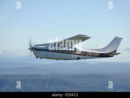 Ein unter Druck stehendes Cessna 210 fliegt über der malerischen Westküste von Neuseeland Stockfoto