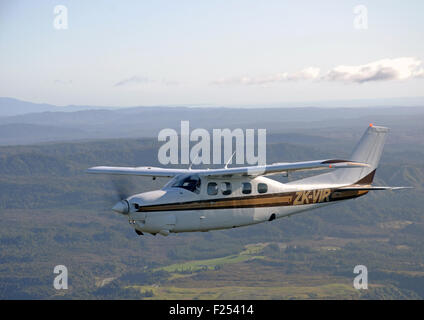 Ein unter Druck stehendes Cessna 210 fliegt über der malerischen Westküste von Neuseeland Stockfoto