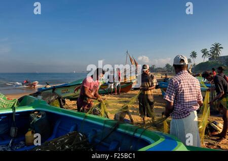 Sri Lanka, Western Province, Negombo, Fischer ihre Netze am Porathota Strand sortieren Stockfoto