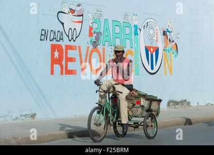 Kuba, Cienfuegos Provinz, Cuenfuegos, Altstadt als Weltkulturerbe der UNESCO, Radfahrer von einer Mauer mit politischer Propaganda aufgeführt Stockfoto