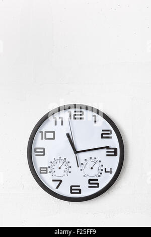 Große schwarze rund um die Uhr auf weißen Wand. Stockfoto