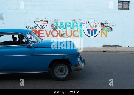 Kuba, Cienfuegos Provinz, Cuenfuegos, Altstadt als Weltkulturerbe der UNESCO, amerikanisches Auto durch eine Wand mit politischer Propaganda aufgeführt Stockfoto