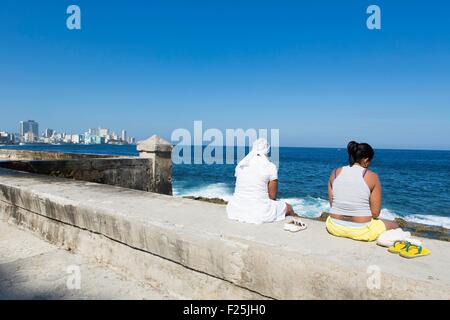 Kuba, Havanna, Ciudad De La Habana Provinz Menschen sitzen, mit Blick aufs Meer auf dem Malecon und Vedado District im Hintergrund Stockfoto