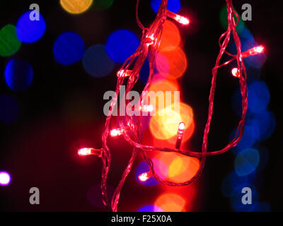 Ein rotes Licht Lampen Draht String auf dem Hintergrund der anderen Farben verwischt Licht für festliche Dekoration für Weihnachten oder Diwali. Stockfoto