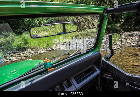 fahren durch einen Bach in einem Jeep mit einem Hula-Mädchen im dashboard Stockfoto