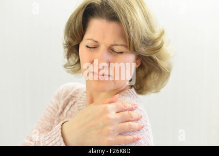 Frau mit Schmerzen in der Schulter auf hellem Hintergrund Stockfoto