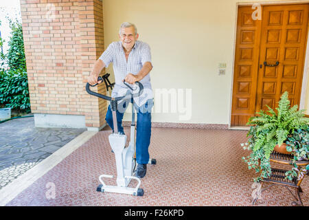 ältere Achtzigjährigen männliche hält fit dadurch Heimtrainer auf der Terrasse des Hauses Stockfoto