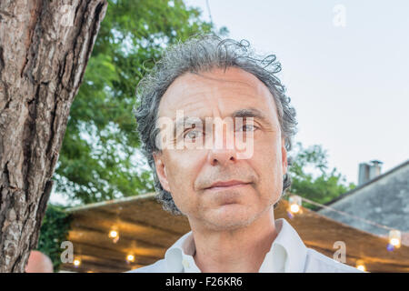 Mann mittleren Alters mit erstaunlichen und stechend grünen Augen in einem weißen Hemd vor einem italienischen Restaurant im freien Stockfoto