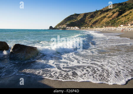 die Wellen brechen sich am einsamen Strand, der Hintergrund blauer Himmel und Wolken Stockfoto