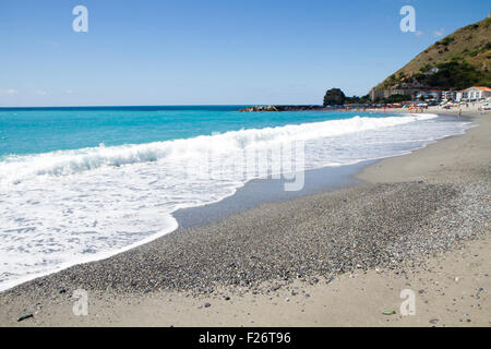 die Wellen brechen sich am einsamen Strand, der Hintergrund blauer Himmel und Wolken Stockfoto