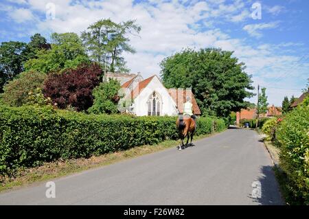 Reiter, vorbei an der St. Mary die Jungfrau Kirche im Zentrum Dorfes, Turville, Buckinghamshire, England, Vereinigtes Königreich, West-Europa. Stockfoto