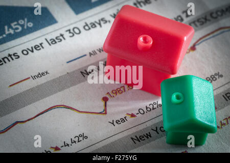Kunststoff Nachahmung Musterhäuser in grünen und roten Farben sitzen oben auf sinkende Börse Preis Diagramme und Grafiken Stockfoto