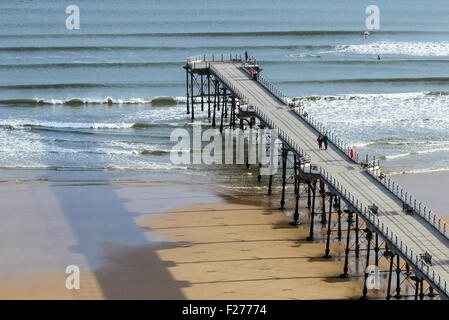 Saltburn am Meer, North Yorkshire, England, UK. Blick über viktorianischen Saltburn Pier mit Surfer reiten Wellen bei Ebbe. Stockfoto