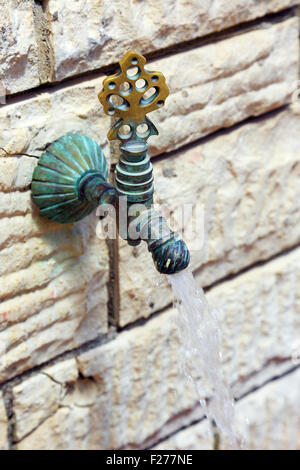 Trinkwasser aus dem Wasserhahn an der Wand fließt Stockfoto