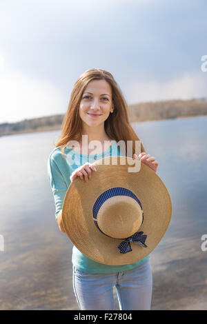 Sommersprossige glückliches Mädchen Stroh Hut in ihren Händen hält und Blick in die Kamera Stockfoto