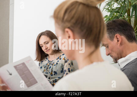 Drei Leute sitzen im Wartebereich des Krankenhauses, München, Bayern, Deutschland Stockfoto