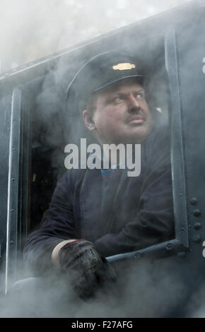 Der Fahrer des einen Dampfzug auf der Keighley & Wert Valley Railway lehnt aus seiner Kabine. Stockfoto